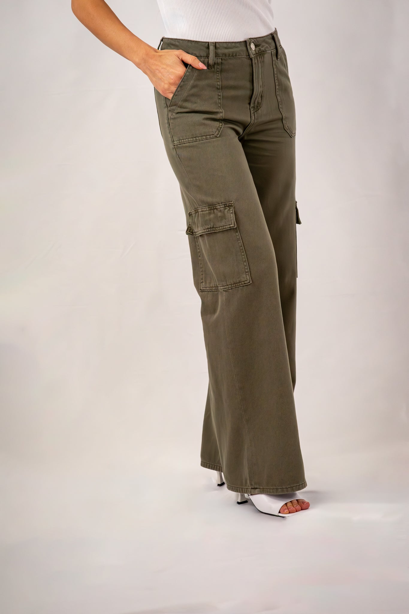  Close-up of olive green wide-leg cargo pants featuring utility pockets and relaxed fit, styled with a white ribbed tank top.