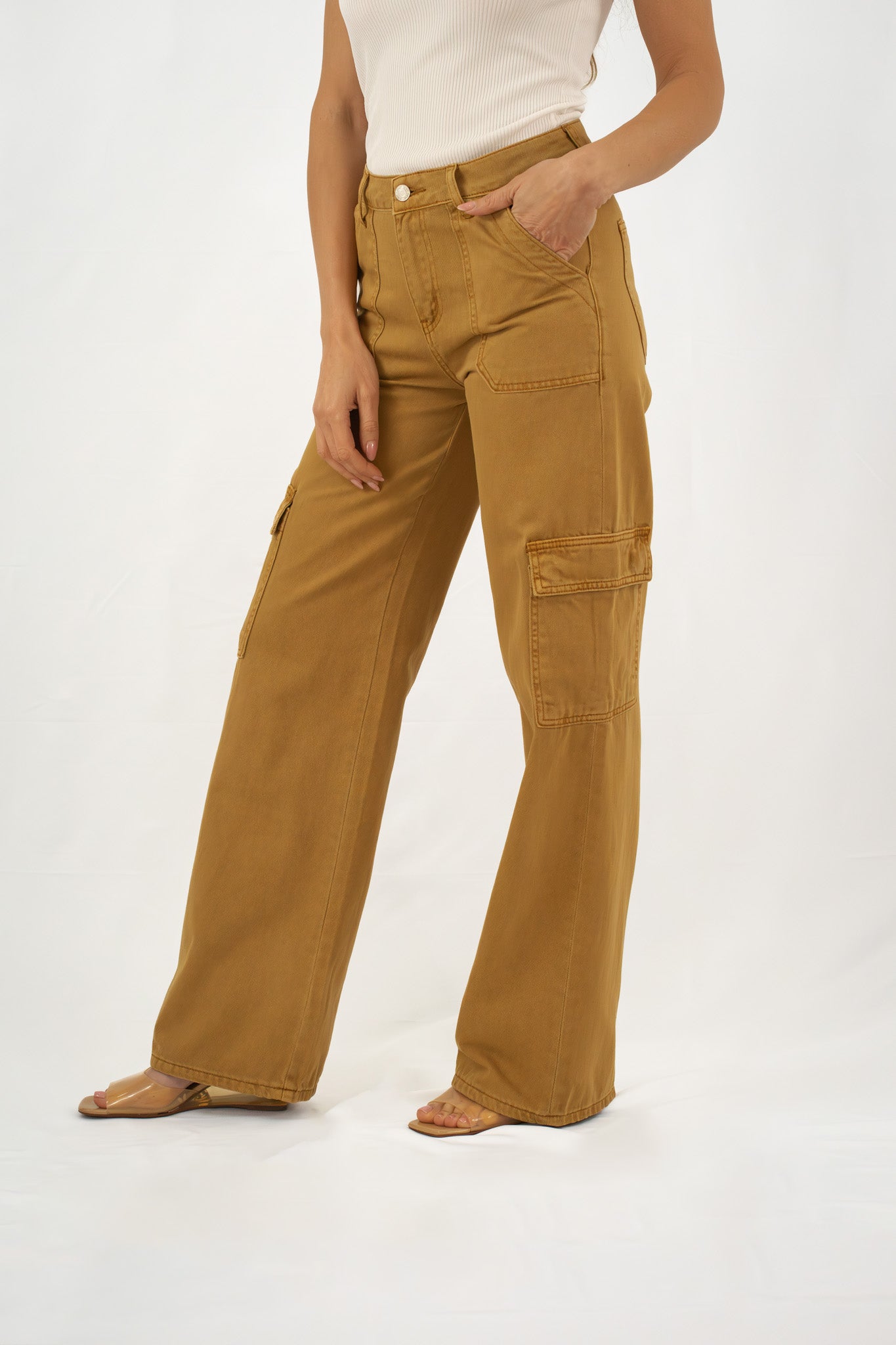 Woman styled in mustard yellow wide-leg cargo pants with utility pockets, paired with a white tank top and neutral heels.