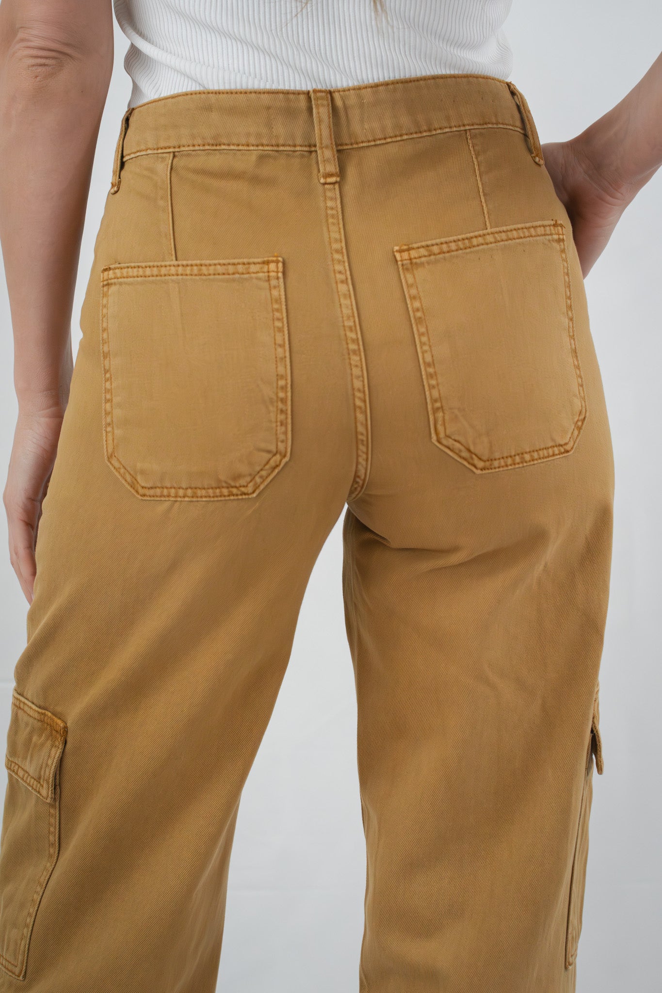 Back view close-up of mustard yellow cargo pants highlighting patch pockets and relaxed fit.