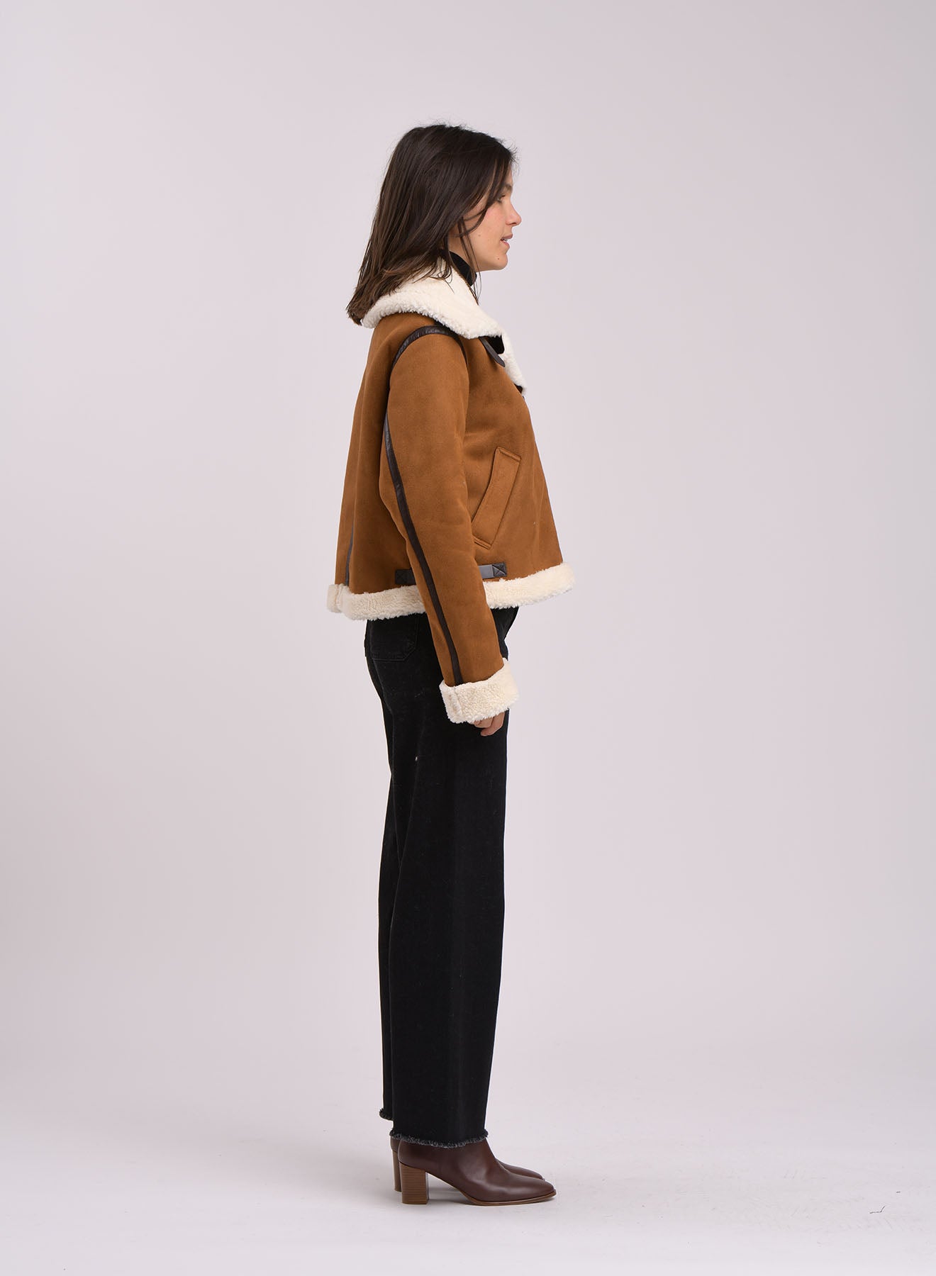 Side view of a cropped womenÕs brown aviator jacket with buckle details and soft shearling trim