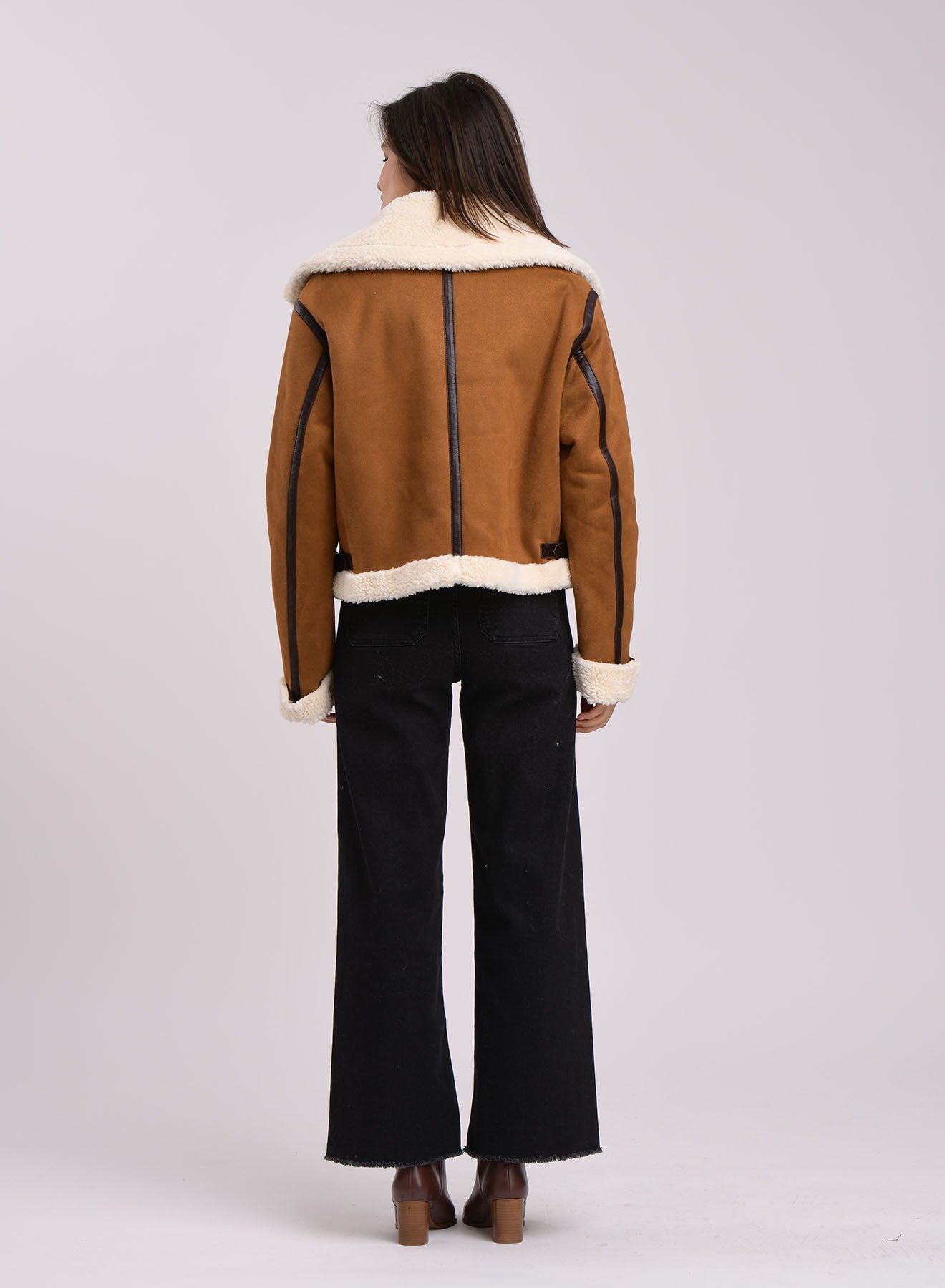 Back view of camel suede aviator jacket with black piping and cream shearling hemline.