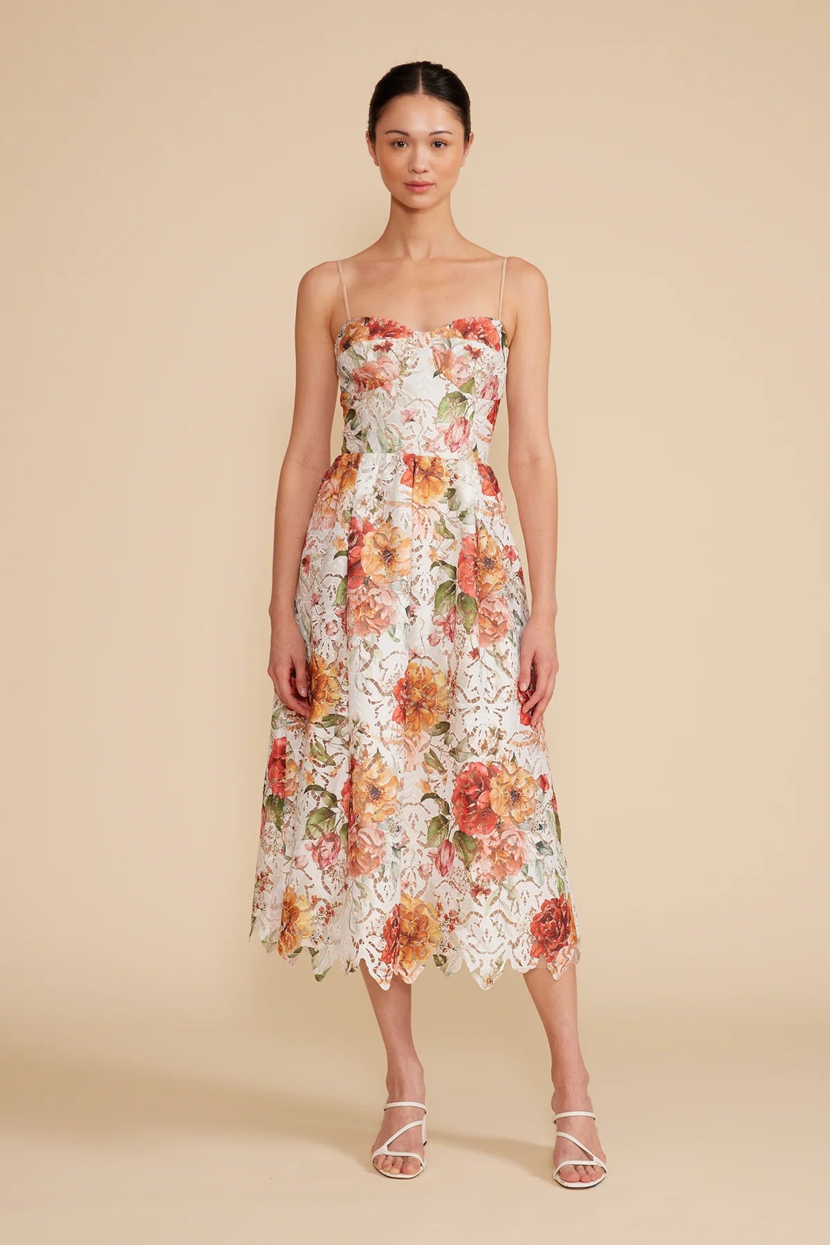 Full front view of the model wearing  Mona lace dress, paired with white sandals.
