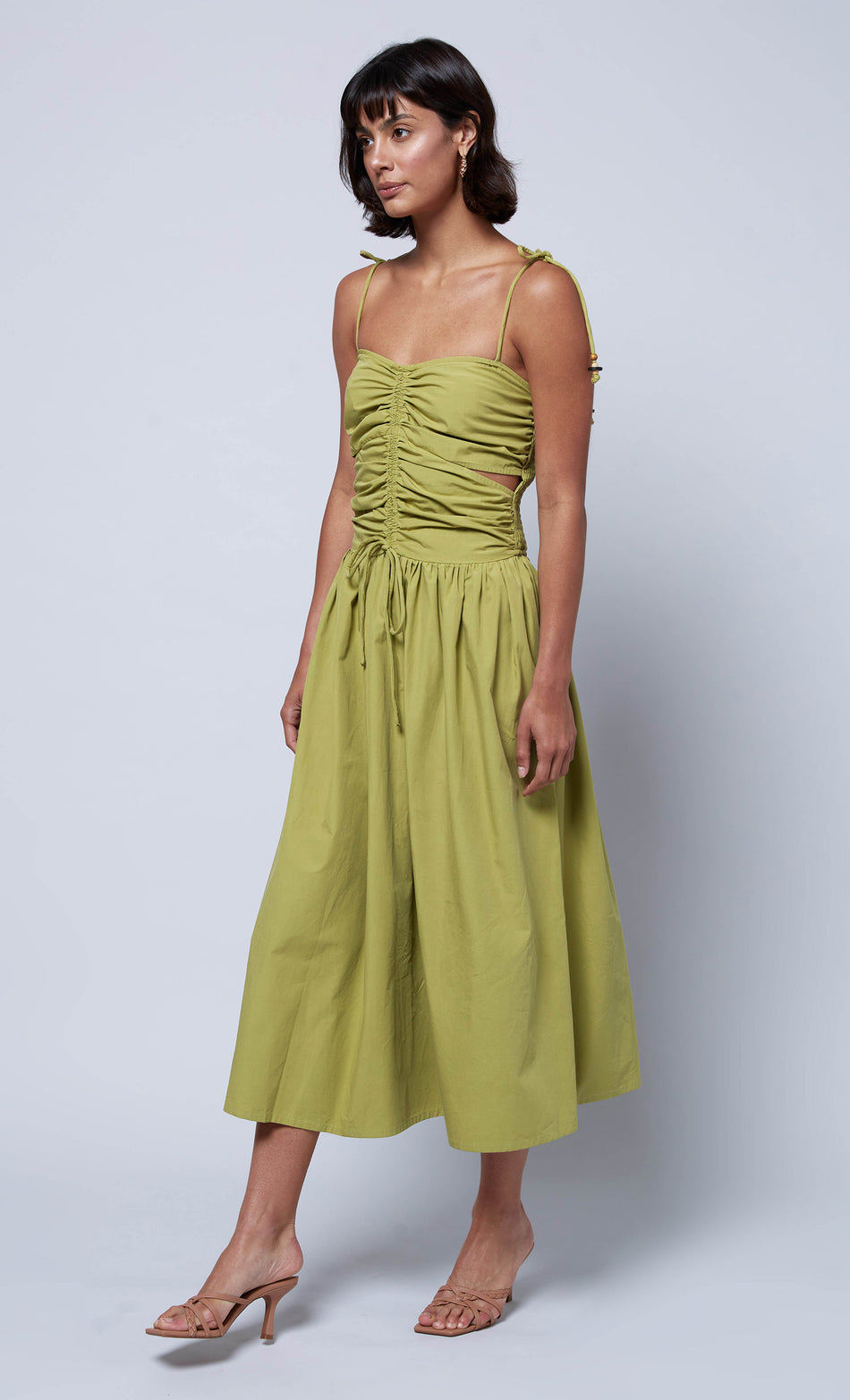 Side-angle view of a green ruched midi dress with tie straps and a flowy skirt, perfect for casual or semi-formal occasions.