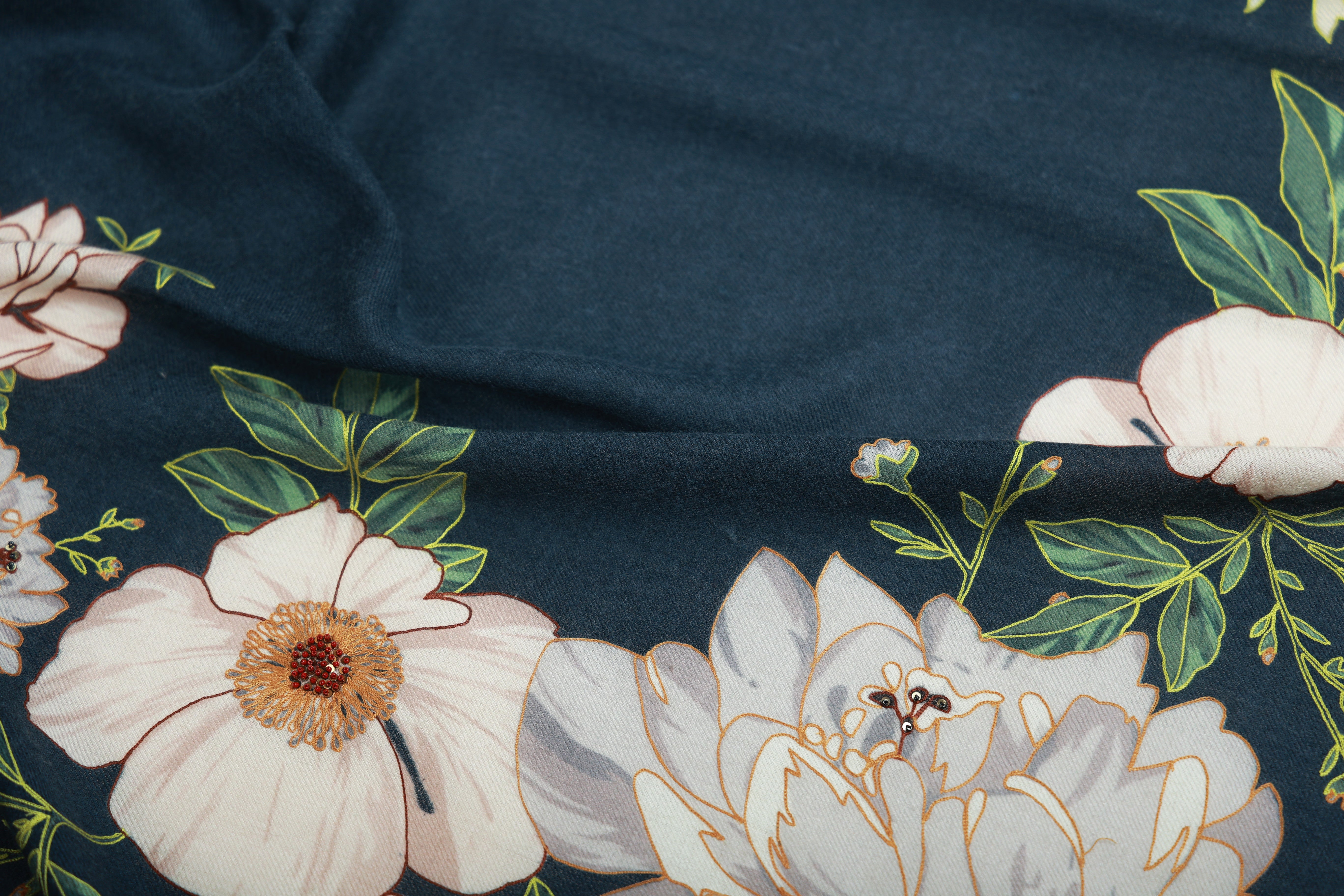 Close-up of a navy blue wool and cashmere shawl featuring a detailed floral pattern in pastel shades, highlighting the soft texture and intricate design.