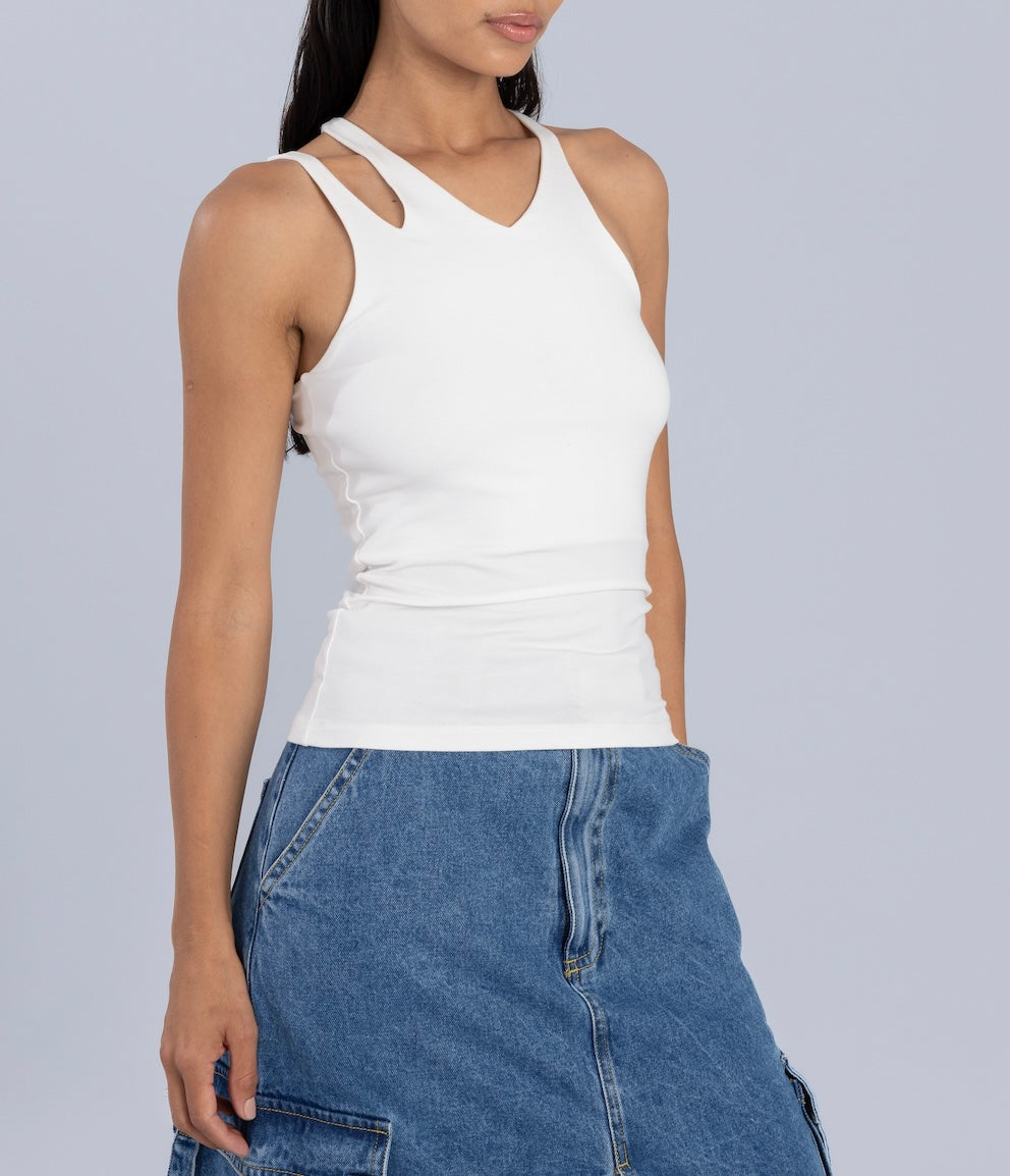 Side profile of a woman in a white racerback tank top and a blue denim midi skirt with cargo-style details, styled against a light gray background.