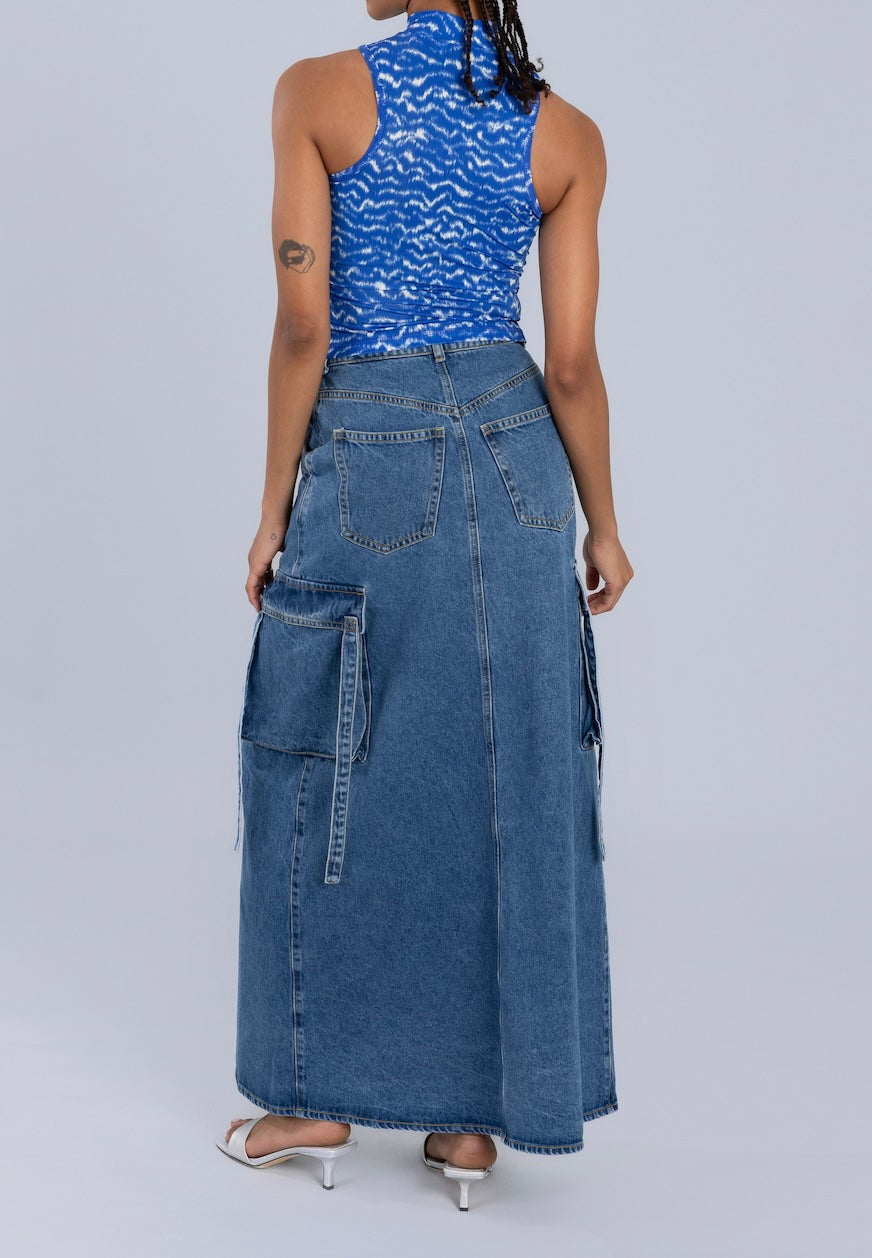 Back view of a blue maxi denim skirt showcasing back pockets and cargo-style accents, styled with a sleeveless blue top.