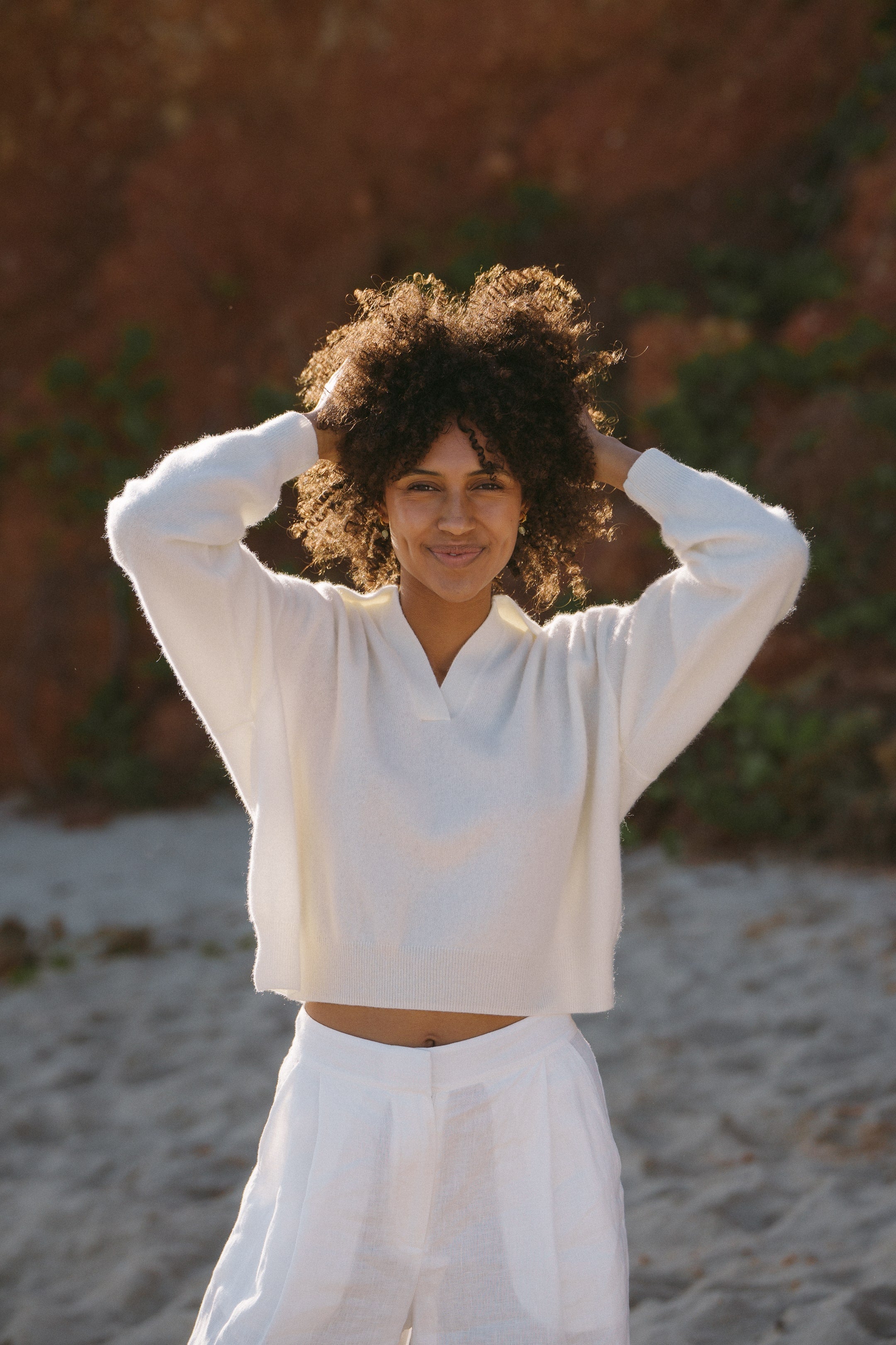 Front view of a woman's luxury ivory cashmere V-neck sweater with a classic collar and ribbed cuffs, highlighting the soft texture and premium quality material.