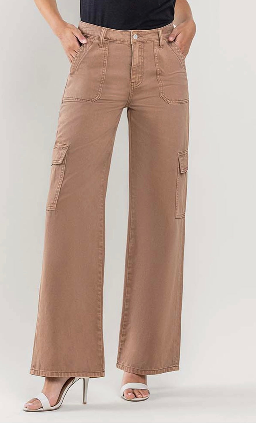 Brown wide-leg cargo pants with utility pockets, styled with a tucked-in black tank top and white open-toe heels.