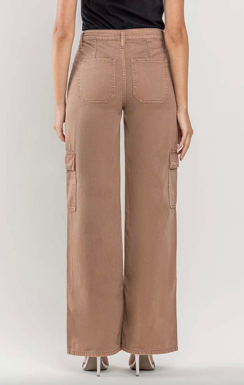 Back view of brown wide-leg cargo pants featuring utility details, paired with a black tank top and white heels.