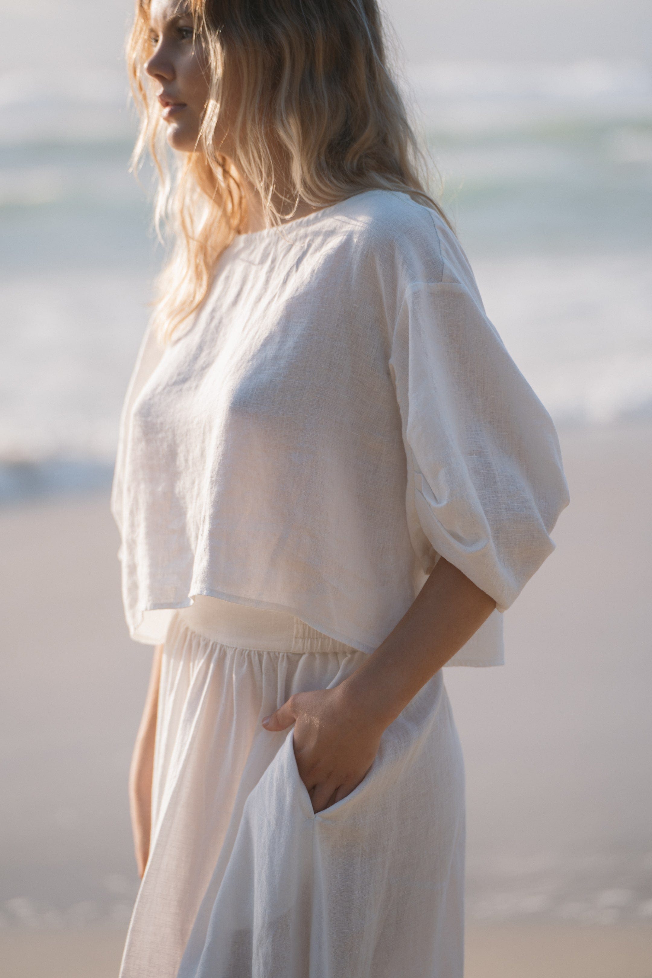 Back view of Leia Linen Top in Ivory, showcasing a straight-cut hem and clean lines across the shoulders, with a concealed zipper, on a white background.